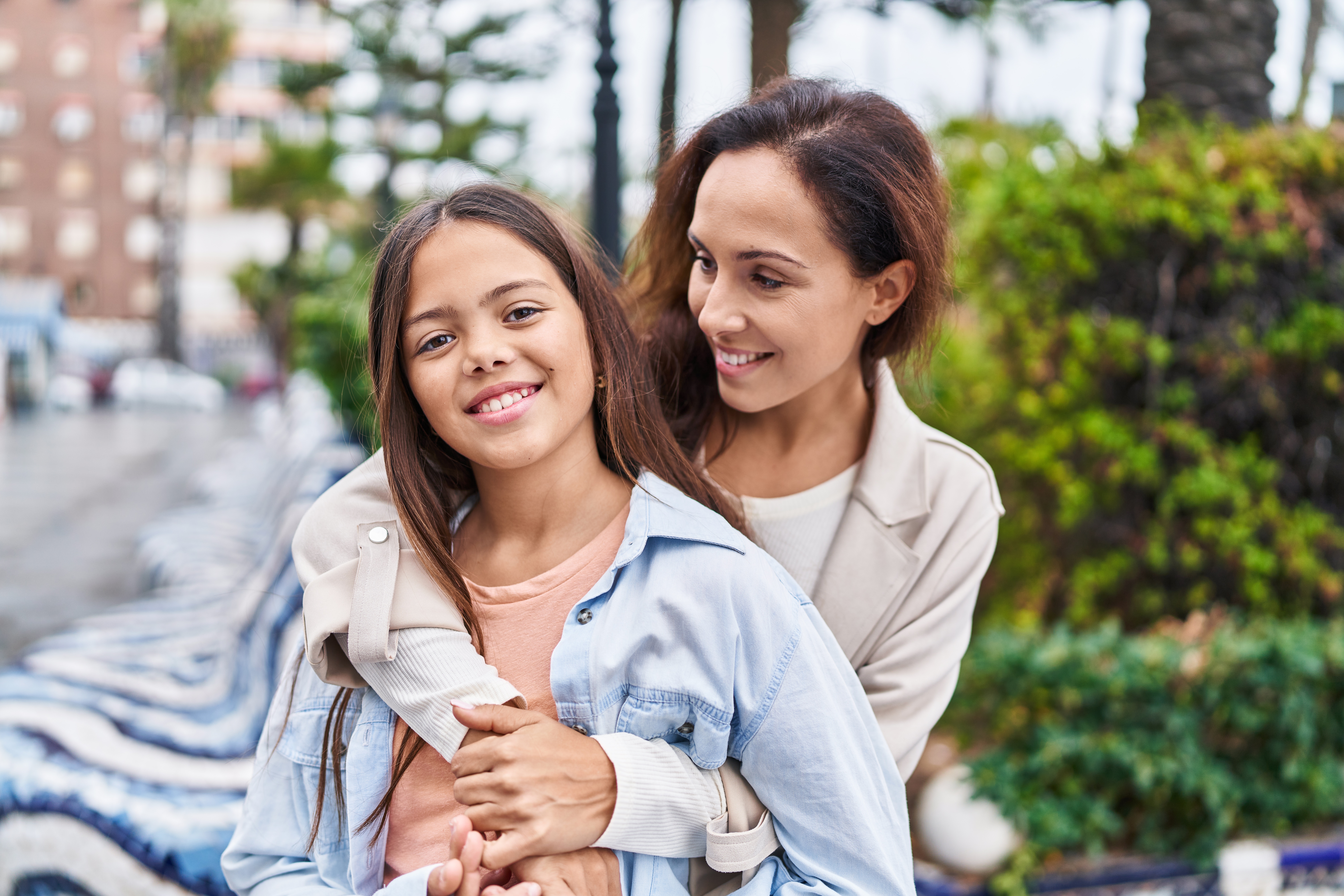 A smiling woman hugging a girl who is also smiling. The photo represents kinship carers.